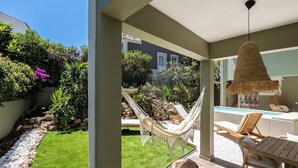 Un espace patio avec une piscine, du mobilier d’extérieur et un hamac.
