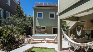 A pool area with lounge chairs, a hammock, and a staircase leading to a second floor.