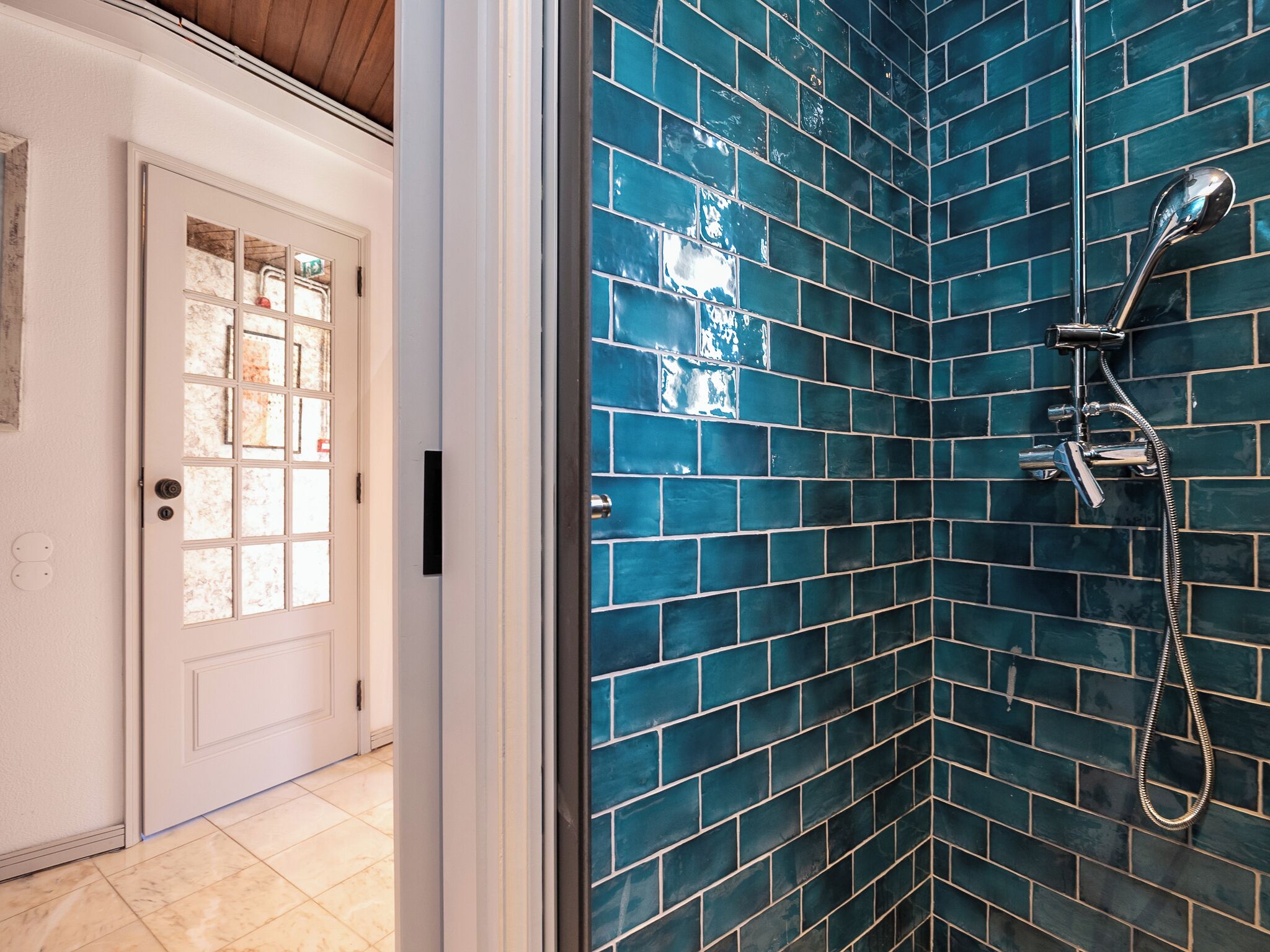 A bathroom with a shower and a door with frosted glass panels.