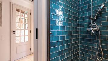 A bathroom with a shower and a door with frosted glass panels.
