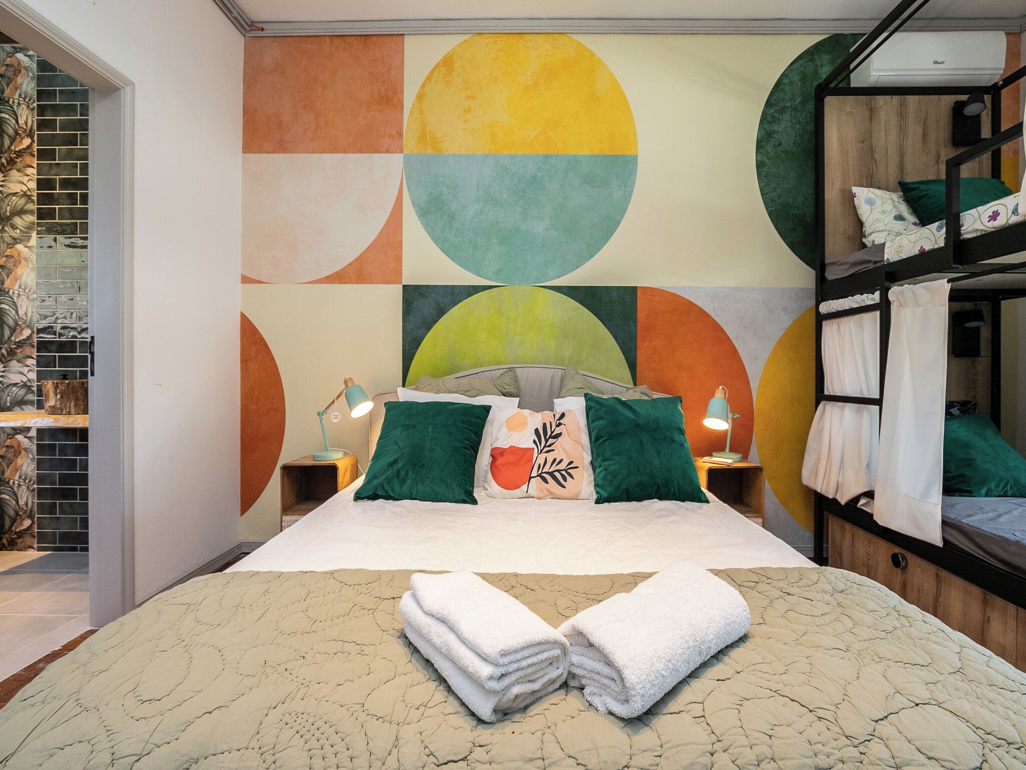 A modern bedroom with a large bed, a colorful abstract wall, and a built-in wardrobe.
