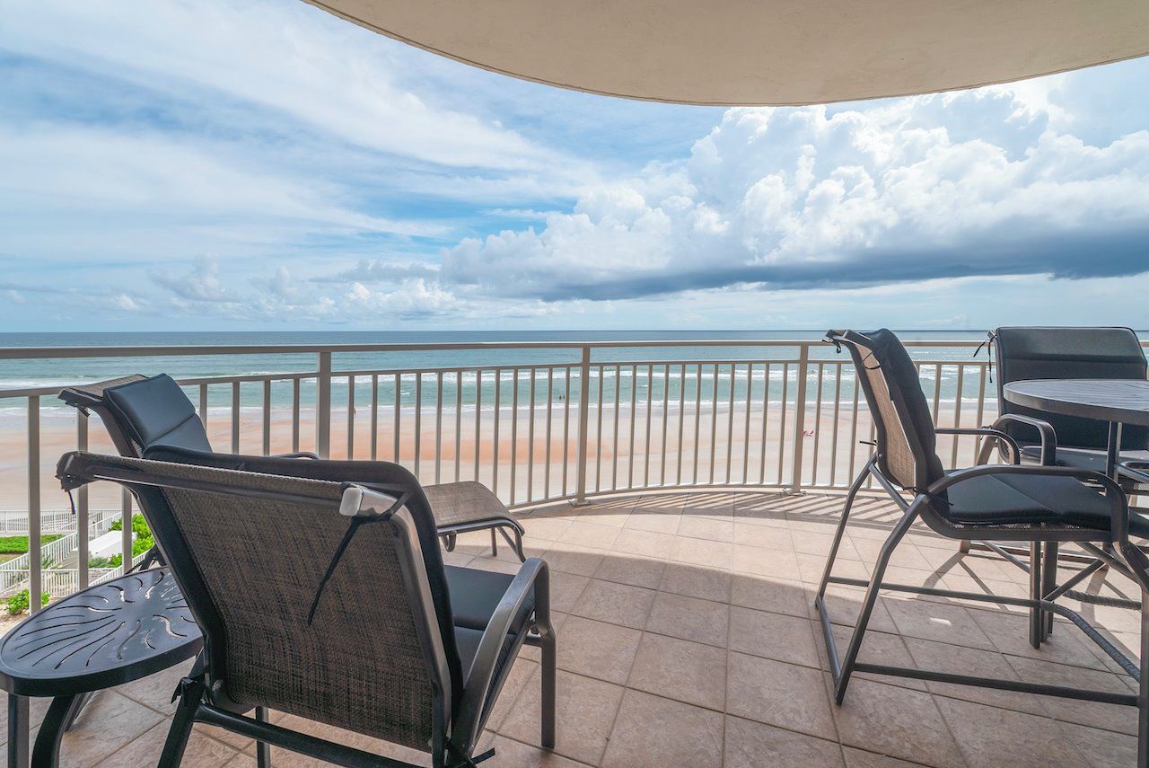 A balcony with outdoor seating and a view of the beach.