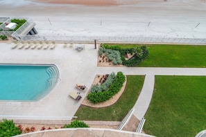 An aerial view of a resort with a swimming pool, lounge chairs, and a landscaped garden area. - #404 St. Maarten 3/3 Luxury Oceanfront Condo Daytona Beach Shores (Daytona Beach Shores)