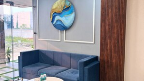 A modern interior with a blue sofa, a marble coffee table, and a decorative wall piece. - Hotel Benchmark Prime (Indore)