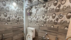 Une salle de bain comprenant des toilettes, un bidet et une douche. Les murs sont décorés d’un motif circulaire.