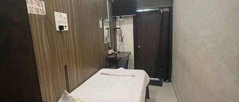 Un pasillo estrecho con una cama, un equipo de aire acondicionado y una puerta.