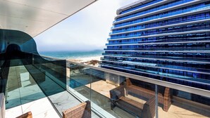 Ett modernt hotell med en balkong i glas som vetter ut mot stranden och havet.