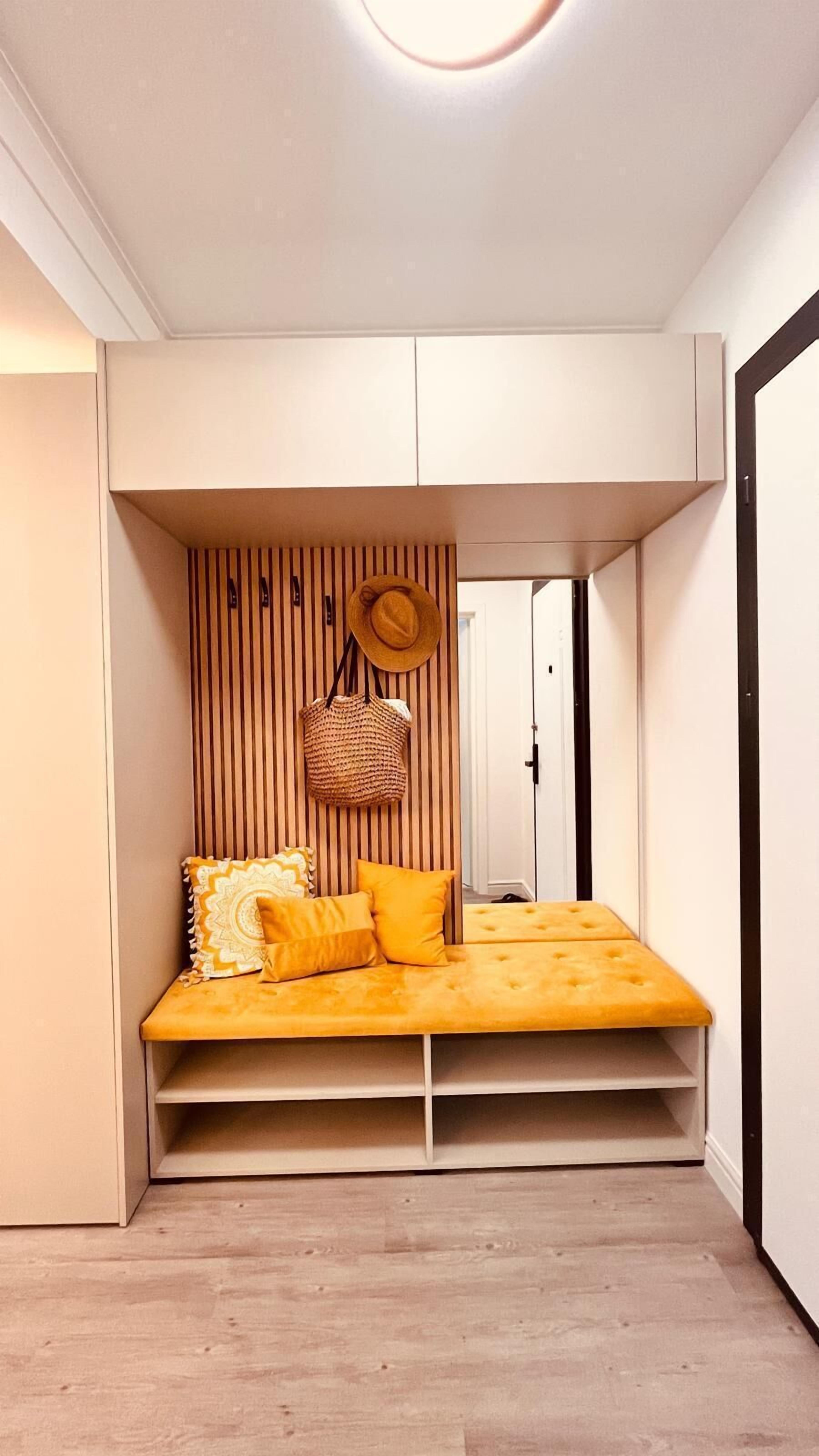 A compact bedroom with a built-in bed, storage cabinets, and a small seating area.