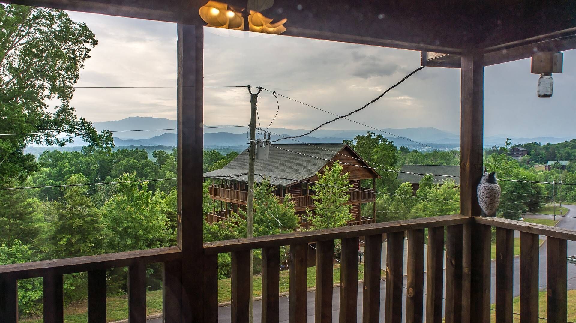 Una baita di legno con un balcone affacciato su una zona boschiva e montagne lontane.
