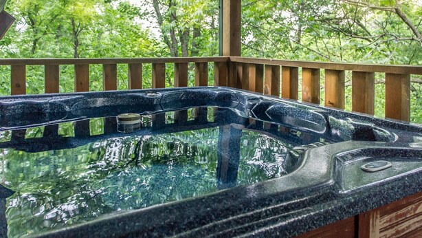 Ein Whirlpool mit einer Holzterrasse und Blick auf Bäume.