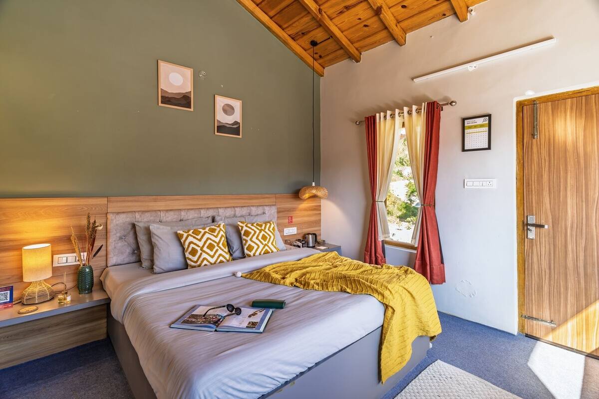Een slaapkamer met een bed, bedlampen, een nachtkastje en een raam met gordijnen.