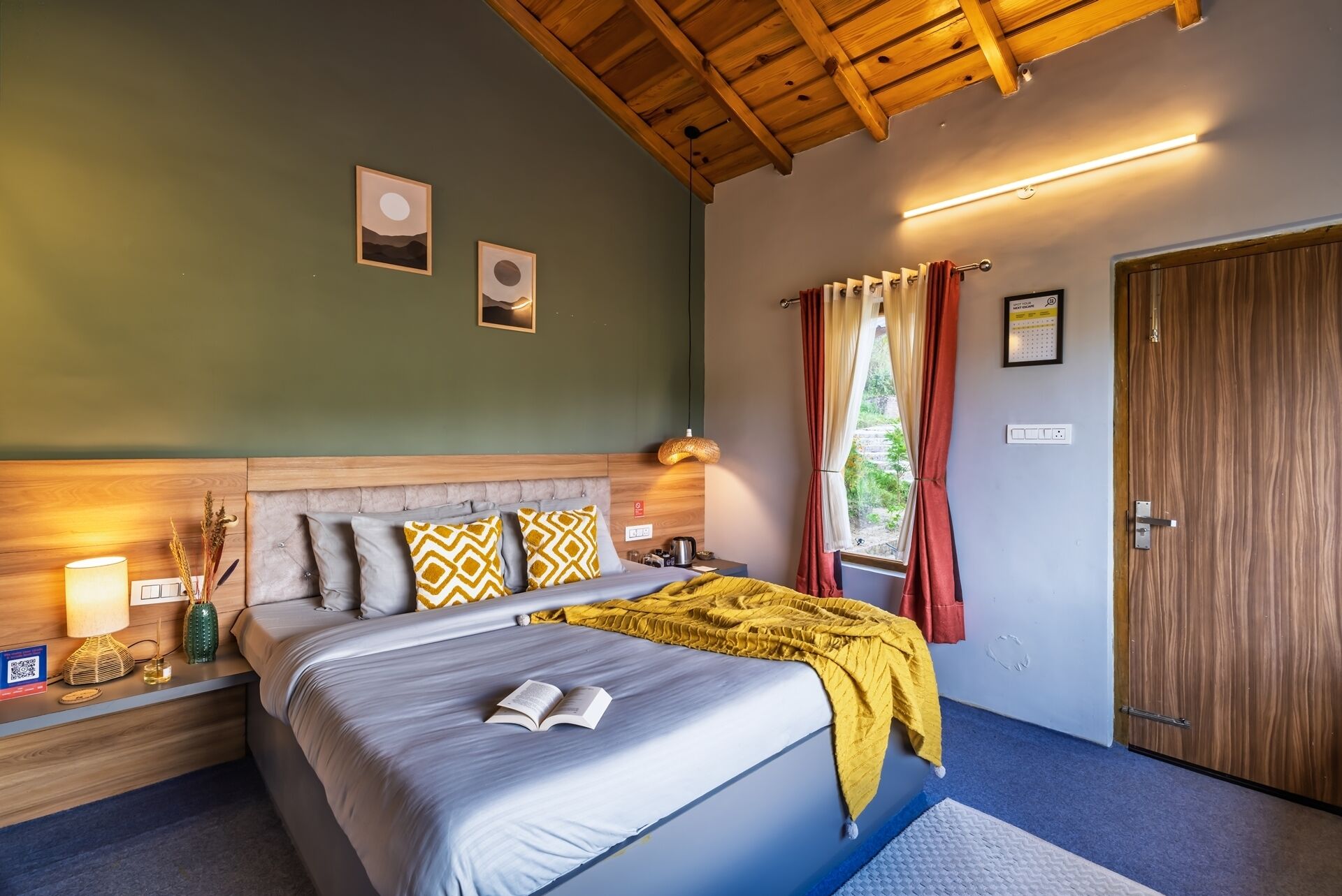 A bedroom with a bed, bedside lamps, a wooden headboard, and a window with curtains.