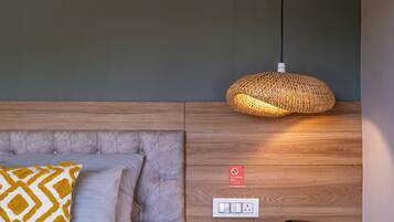 A modern hotel room with a bed, a bedside table with a lamp, a coffee maker, and a "No smoking" sign.