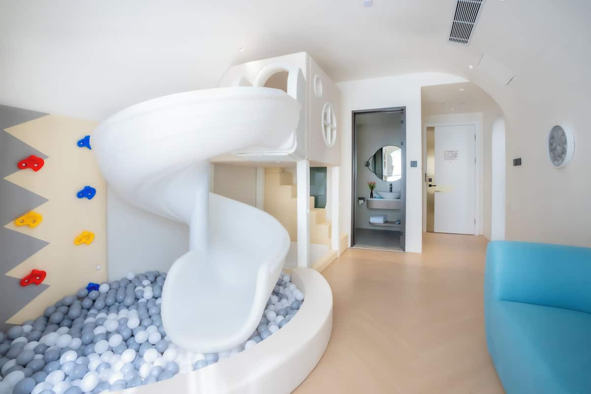 Un interior moderno con una zona de juegos, un tobogán en espiral y un sofá azul.