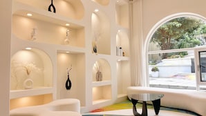 Un intérieur moderne avec des murs blancs, un éclairage encastré et une grande fenêtre donnant sur un paysage verdoyant.