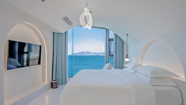 Une chambre moderne avec un grand lit, un téléviseur à écran plat et une vue sur la mer.