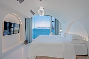 A modern bedroom with a large bed, a flat-screen TV, and a view of the sea. - Dali Canghai Xueyue Seaview Hotel (Dali)