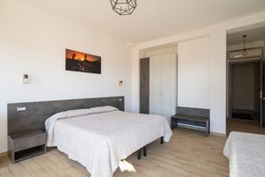 A bedroom with a bed, bedside tables, a wardrobe, and a painting on the wall. - Triple room with private bathroom (Jerzu)