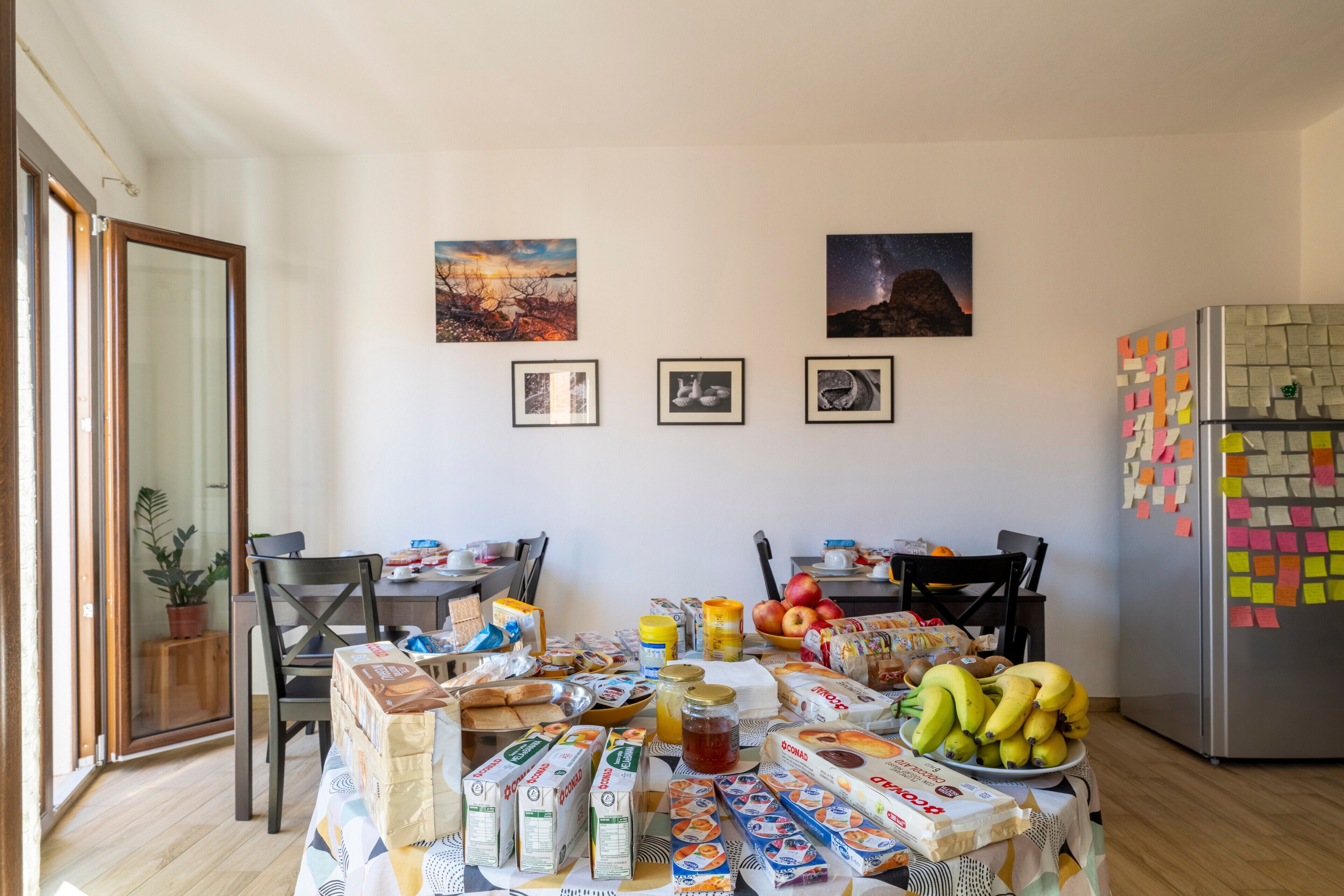 Zona pranzo con tavolo apparecchiato per la colazione, con diversi cibi e condimenti.