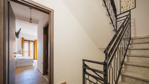 Eine Treppe mit Metallgeländer, Holzboden und einem Bett im angrenzenden Zimmer.
