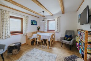 Una habitación acogedora con una mesa de madera, sillas, una estantería y un televisor.