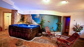 Ein Wellnessbereich mit Whirlpool, Holzstühlen und einer Steinwand mit Pflanzen.