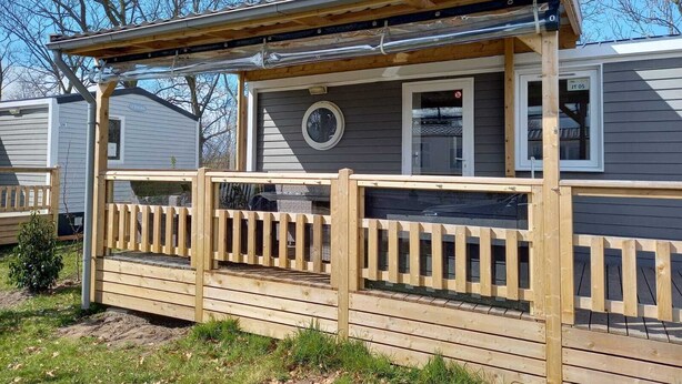 Une terrasse en bois avec un porche couvert et une petite fenêtre.