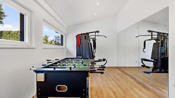 A room with a foosball table, exercise equipment, and a large mirror.