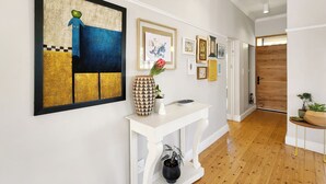 Un couloir avec une console blanche, une grande peinture abstraite et plusieurs tableaux encadrés accrochés au mur.