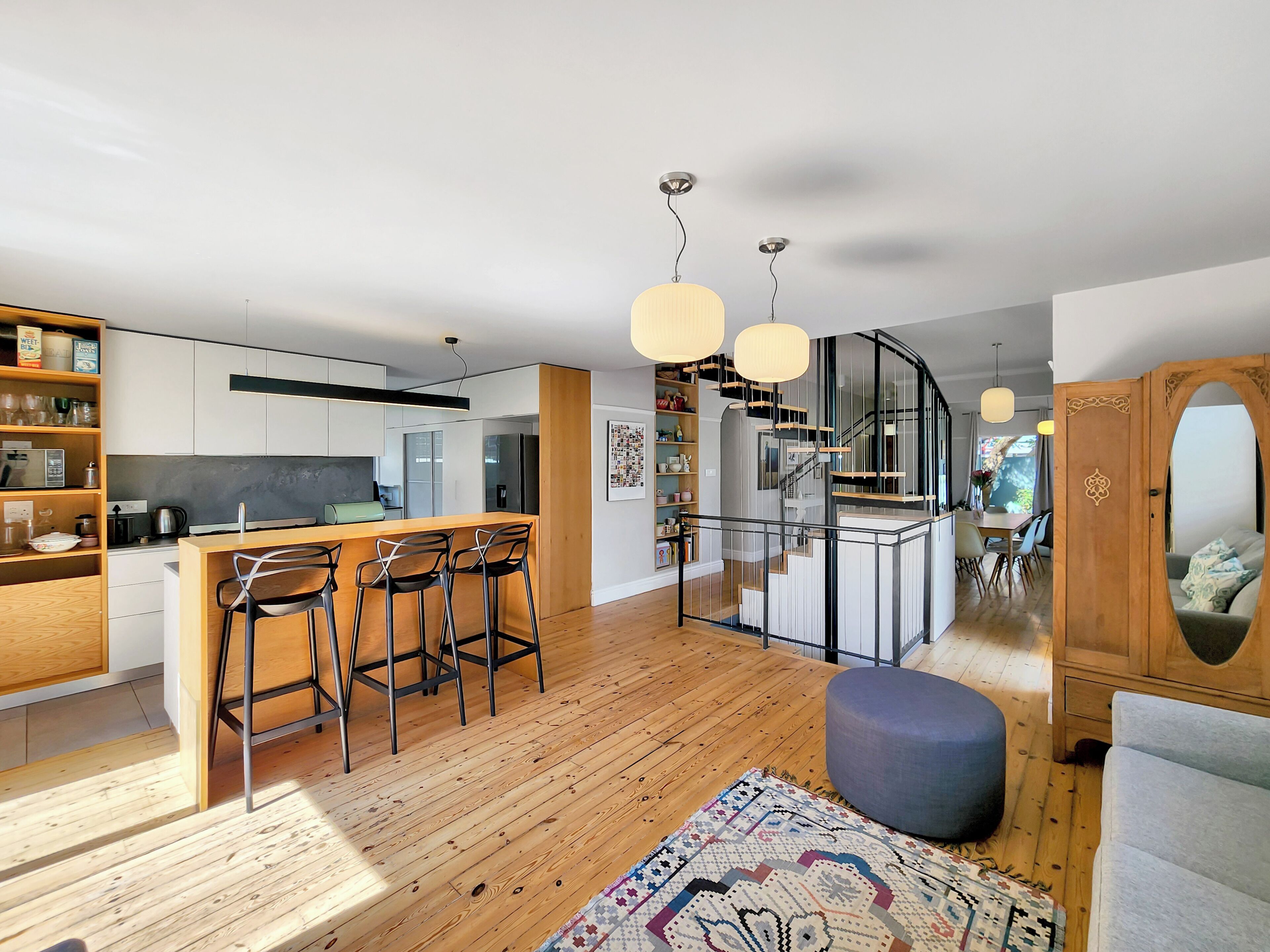 A modern kitchen with a central island, bar stools, and pendant lighting.