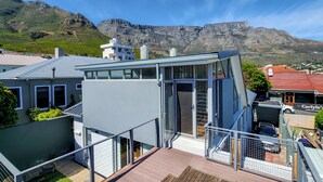 Une maison moderne dotée d’une véranda en verre, d’une terrasse en bois et offrant une vue sur les montagnes.