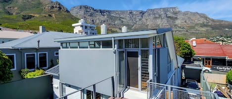 A modern house with a glass conservatory, a wooden deck, and a view of the mountains.
