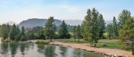A tranquil lakeside setting with a dock, trees, and a distant mountain range.