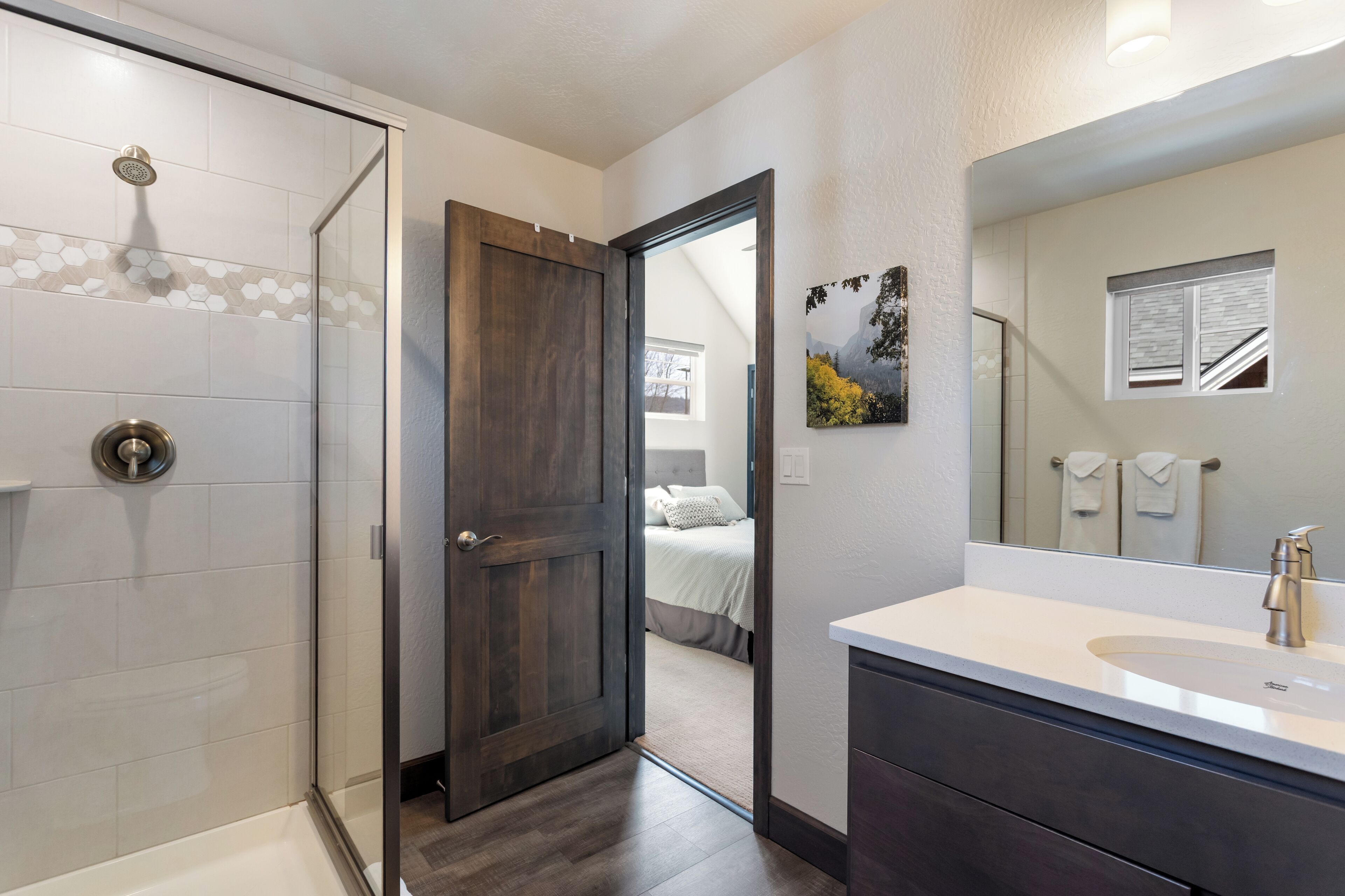 Un baño moderno con ducha, un espejo grande y tocador.
