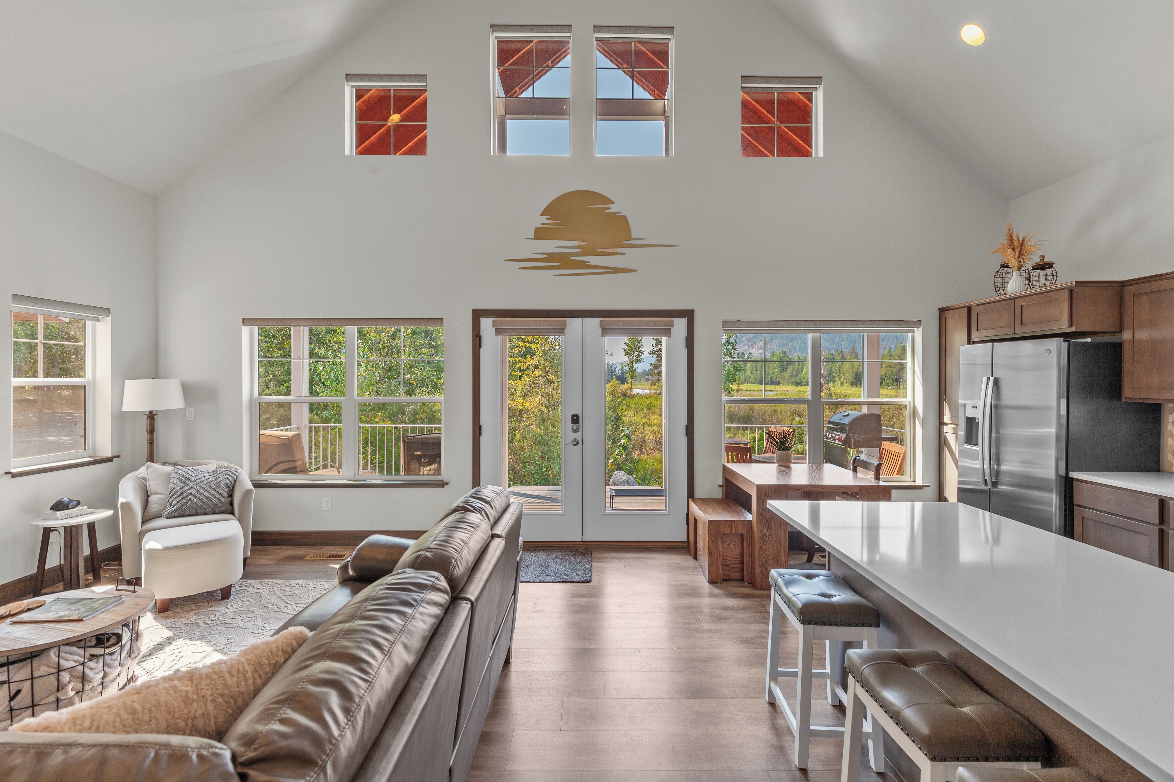 A spacious living area with a large sofa, a dining table, and a kitchen with a refrigerator.