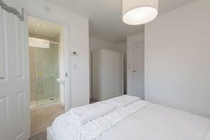 A bedroom with a bed, a walk-in closet, and a glass shower.