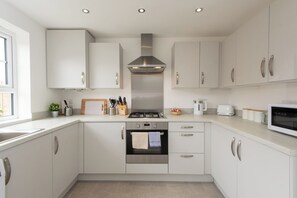 A modern kitchen with white cabinets, stainless steel appliances, and a window providing natural light.