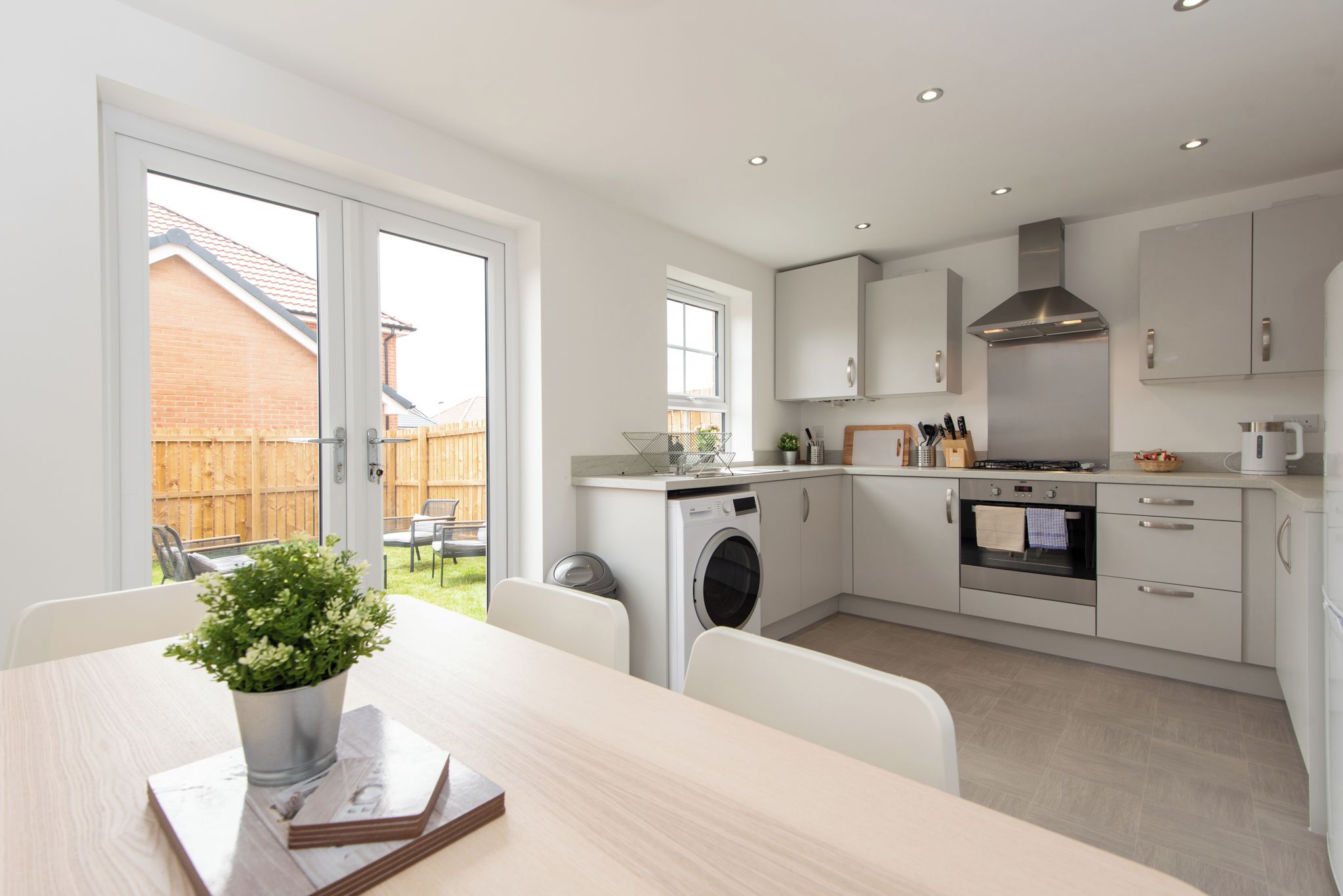 A modern kitchen with white cabinets, a stainless steel range hood, and a built-in oven.