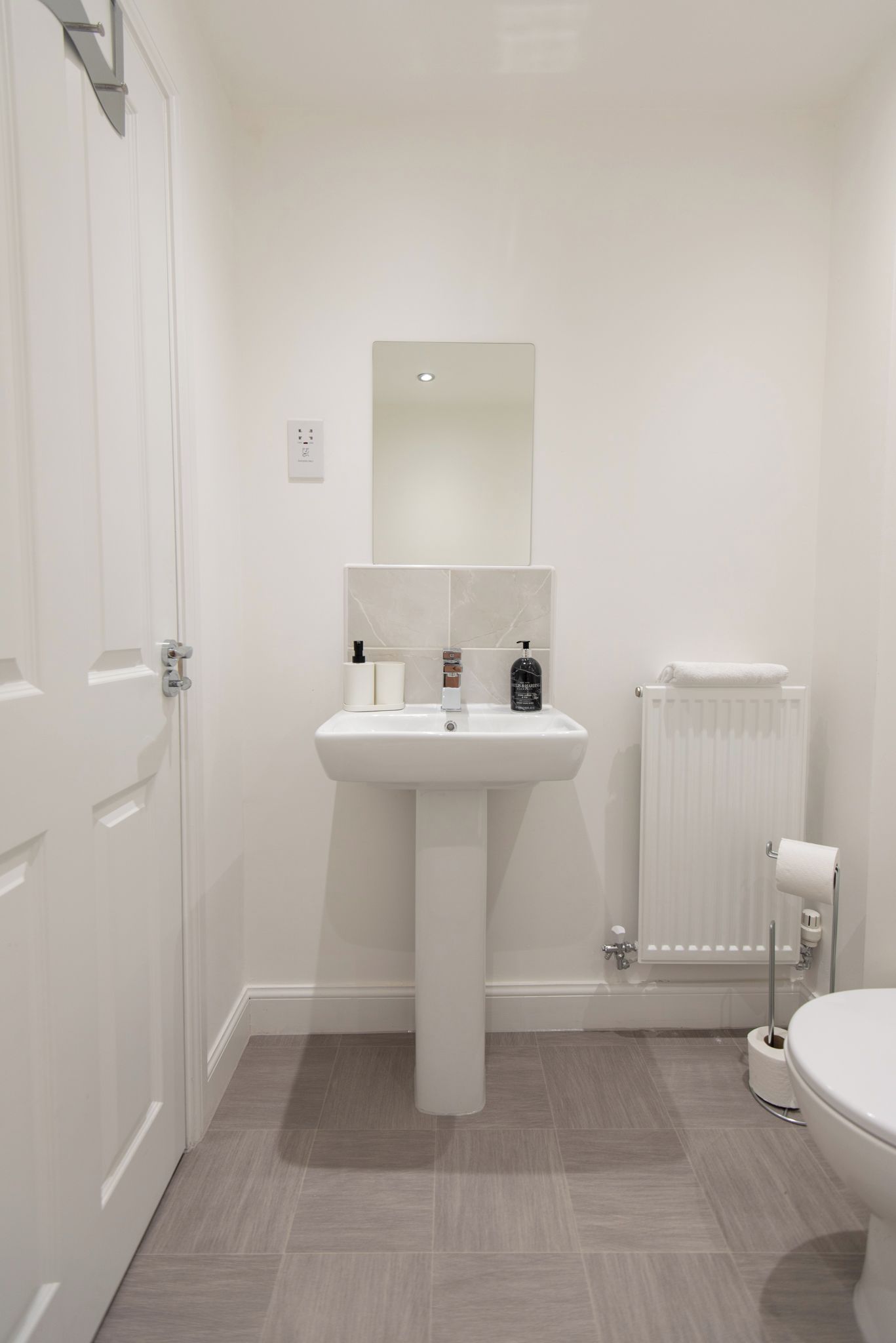 A bathroom with a white sink, mirror, and toilet.