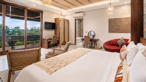 A bedroom with a large bed, two chairs, a desk, a TV, and a view of greenery. - 5-BR Beach Villa in Canggu Overlooking Rice Fields (Kuta Utara)