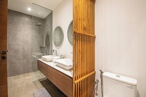 Un bagno moderno con un mobile vanitario in legno, due lavabi, un water e una cabina doccia in vetro.