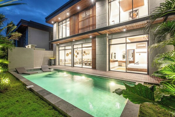 Una casa moderna su due piani con piscina, ampie finestre e interni luminosi.