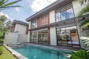 Una casa moderna a due piani con piscina, ampie finestre e un balcone.