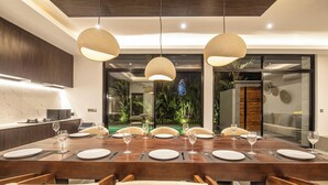 Un espace repas moderne avec une longue table en bois, dressée pour six personnes, entourée de chaises rembourrées.