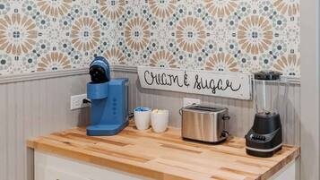 A kitchen with a wooden countertop, a coffee maker, a toaster, and a blender.
