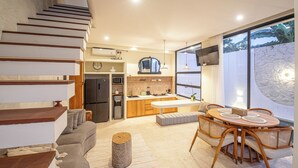 A modern kitchen with a central island, a dining area with a round table, and a staircase leading to an upper level. - Modern 2BR Villas • Stylish Stay in Central Canggu (Canggu)