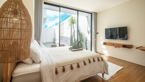 A modern bedroom with a large bed, a television, and a view of the outdoors. - Modern 2BR Villas • Stylish Stay in Central Canggu (Canggu)
