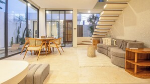 A modern living room with a sofa, coffee table, and dining area with chairs. - Modern 2BR Villas • Stylish Stay in Central Canggu (Canggu)
