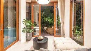 A modern living room with a sofa, a round black coffee table, and a large potted plant. - Elegant 1BR Retreat • Jungle View Hideaway in Ubud (Ubud)