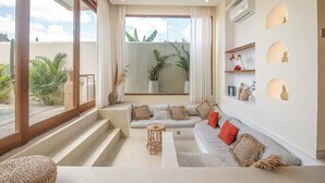 A modern living room with a large window, a sofa set, a coffee table, and a staircase leading to an outdoor area. - Chic Villa Living, Hidden in the Calm of Tumbak Bayuh (Canggu)